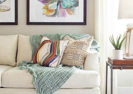 Staged white couch with a teal blanket and two pillows.