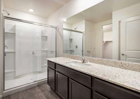 The Roosevelt master bath room shown with granite sink countertops and a glass walk in shower.