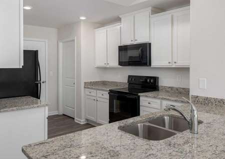 Alamance kitchen with granite counters, white cabinets, and black appliances