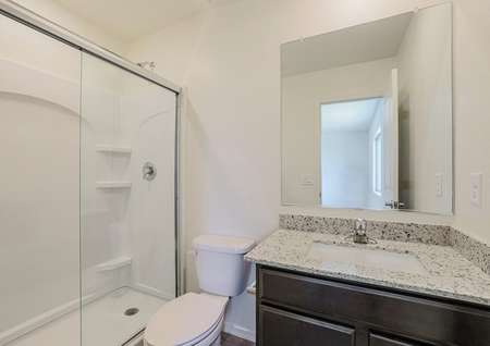 Master bathroom with granite countertops and a white-tiled shower.