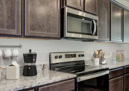 Staged kitchen with stainless steel appliances, brown cabinets and brown flooring.
