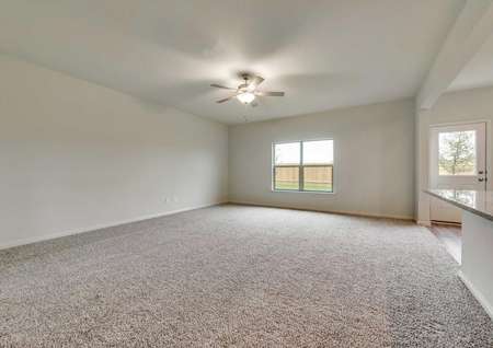 Oakmont floor plan's spacious living room with carpet, ceiling fan and large exterior window 