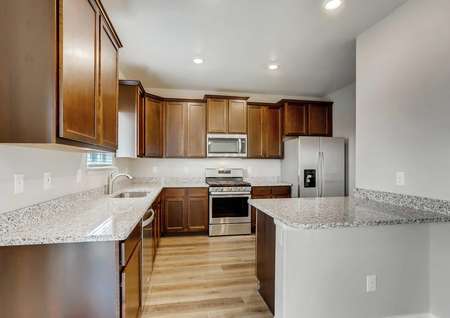 Mesa Verde finished kitchen with brown cabinets, wood floors, and granite countertops