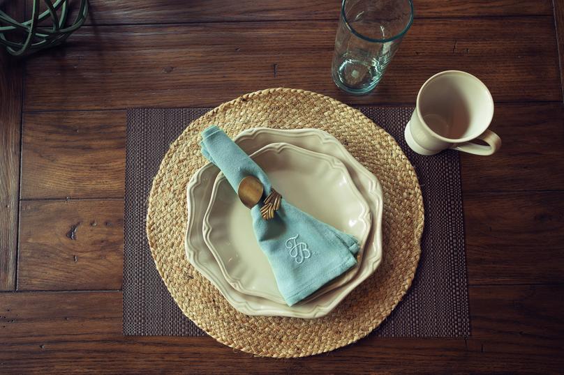 Wooden kitchen table with placemat, plates and napkin.