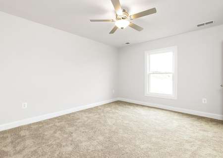 Photo of the primary bedroom with carpet, ceiling fan and window.