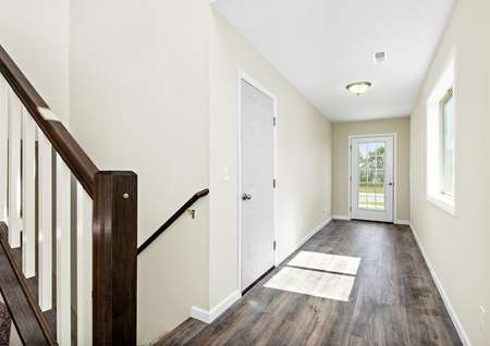 Photo of a spacious foyer with a window, plank flooring, a door the garage and view of the stairs in a split-level home.