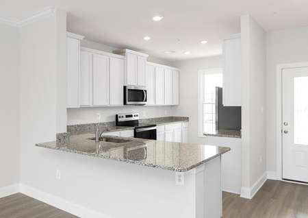 Modern kitchen with white cabinets, recessed lights, stainless appliances and natural light.