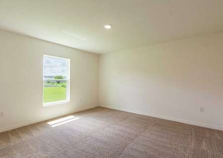 The Cocoa floor plan's spacious master bedroom with a window, white wall, brown carpet and ceiling light fixtuer.