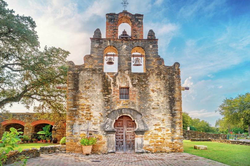 San Antonio, Texas Mission Espada built in the early 18th century showing stone facade, arched wooden door entry, and bells in the belfries