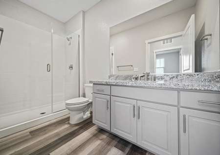 Guest bathroom with a walk-in shower, white cabinets, and granite countertops.