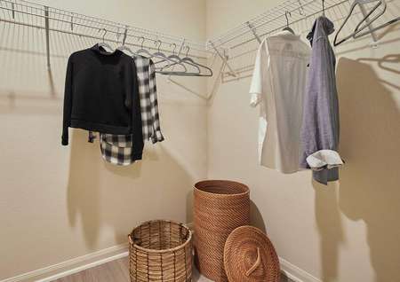 Staged closet with shirts on hangers and two woven baskets.