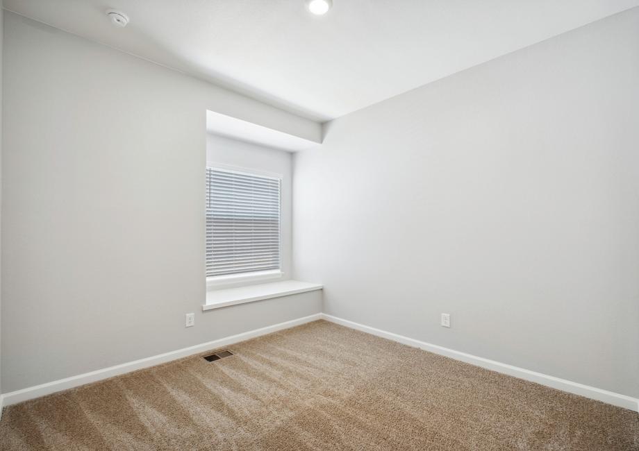 Guest bedroom with a window seat and tan carpet.