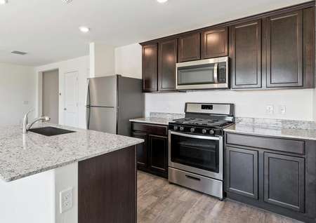 Kitchen with stainless steel appliances, wood-like flooring, and granite countertops.