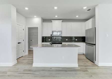 Stunning kitchen with a large granite island, tile backsplash, and wood flooring. 