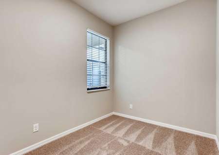 Secondary bedroom in the Mateo model home. Tan walls, baseboards and darker tan carpeting