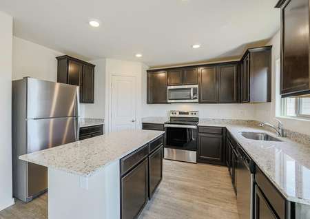 Modern kitchen with dark cabinets, beautiful granite countertops and stainless steel appliances.