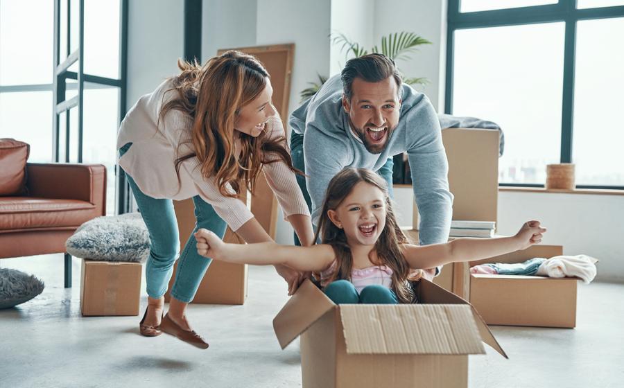 Stock photo of a cheerful young family smiling and unboxing their stuff while moving into a new home.