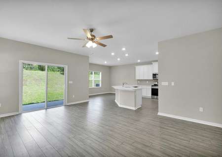 View of the family room, dining room and kitchen with natural light throughout the entertainment space.