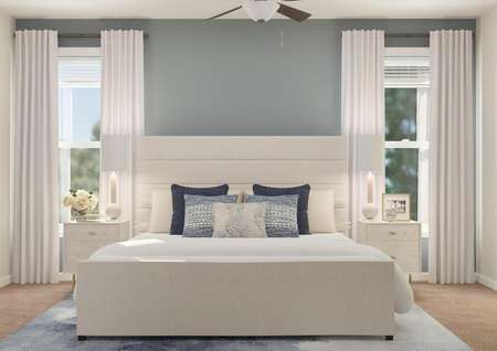 Rendering of the spacious master suite in
  the Anna floor plan, which has two windows, a ceiling fan and carpeted
  flooring. The space is decorated with a large bed, two nightstands, a blue
  rug and a mirror.