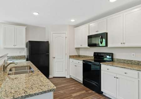 Avery home kitchen with brown granite counters and black appliances