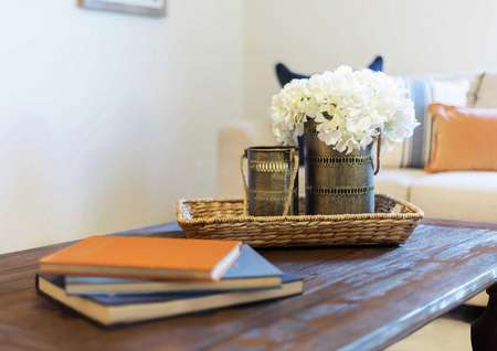 Staged model home with books, woven tray, and white flowers in a coffee can on a wooden table