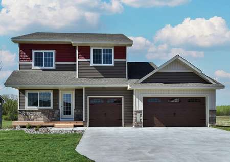 Photo of the front exterior of the two-story St Andrew home at Miske Meadows with taupe and red siding and 3-car garage.