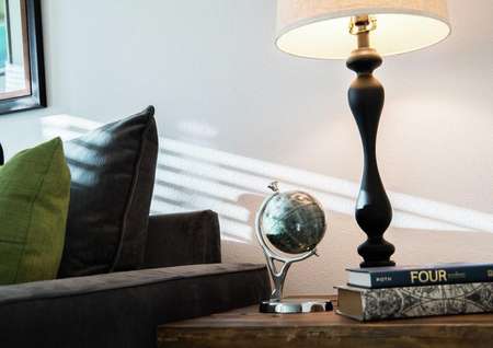 Sea Forest Beach Club model home staged with dark blue sofa and a small globe and lamp sitting on side table