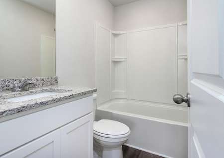 Guest bathroom with a granite countertops and white cabinets.
