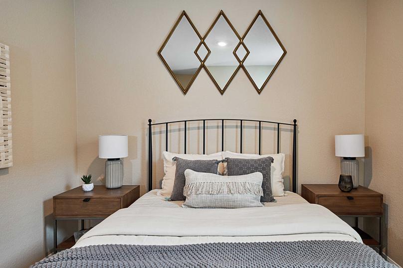 Staged bedroom with large bed, two nightstands, and wall decor.