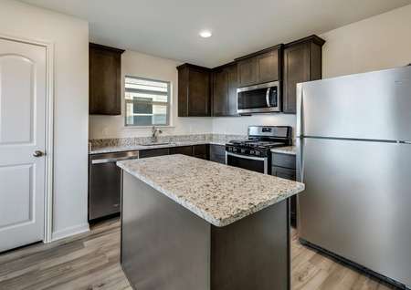 The kitchen has brown cabinetry and stainless steel appliances.