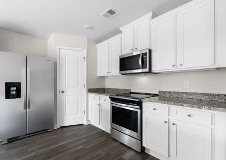 Kitchen with vinyl floors, stainless steel appliances, granite countertops and white cabinetry with hardware. 