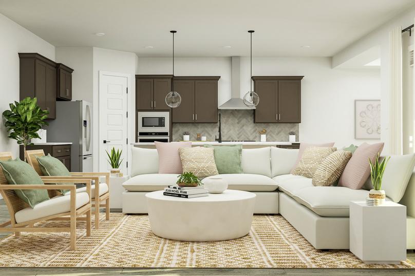 Rendering of the open living space of the
  McAlester floor plan featuring a large white sectional, two accent chairs,
  short table, and dÃ©cor with a view of the kitchen in the background.Â 