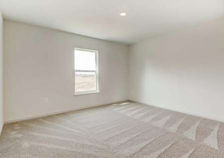 Large bedroom upstairs with light grayish-beige carpet, single recessed light, single window.