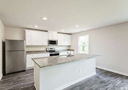 Kitchen with granite countertops, an island, stainless steel appliances and white cabinets.