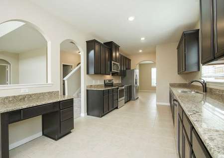 Kitchen with tech station, tile flooring, granite counters, stainless appliances, and dark cabinets in the Redwood model