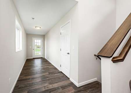 Photo of a long foyer with a window and plank flooring and door from the garage.