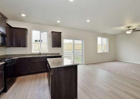 Cypress kitchen with granite counters, wood cabinets, and recessed lights overlooking living room