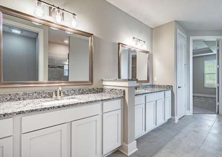 Master bathroom with dual-sink vanity, granite countertop, and framed mirrors.