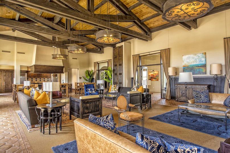 Indoor gathering area with couches, coffee tables, chairs, and elevated ceilings in the Estrella community