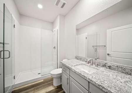 Secondary bathroom with a walk-in shower, granite countertops, and white cabinets.