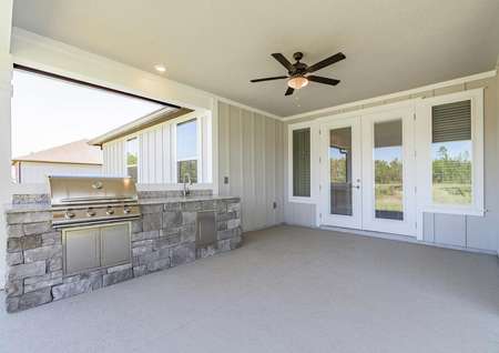 Covered outdoor kitchen with grill, sink, fan and french doors.