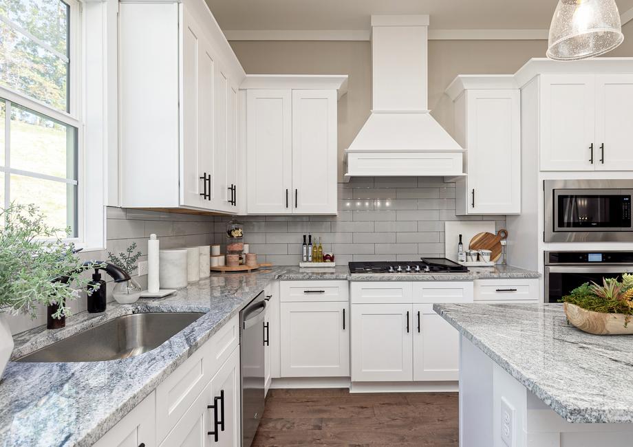 Kitchen with white cabinets, granite countertops and stainless appliances.