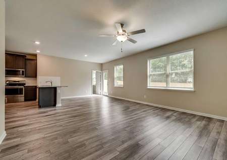 Saint Clair great room with brown walls with white baseboards, large backyard windows, and white backyard door with glass window