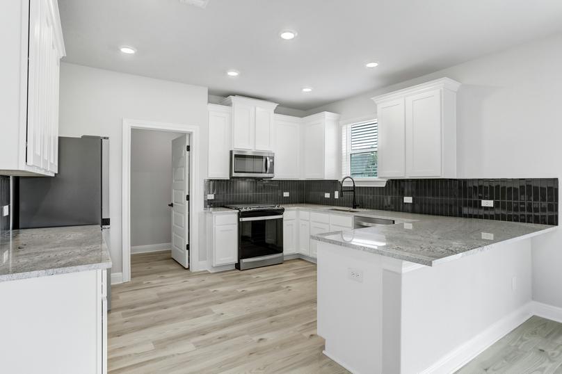 Chef-ready kitchen with stainless appliances, white cabinetry with crown molding, and recessed lighting.