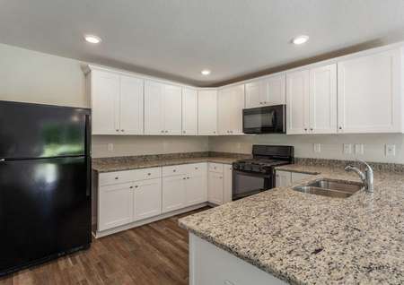Fripp kitchen with black refrigerator, granite countertops, and white cabinets