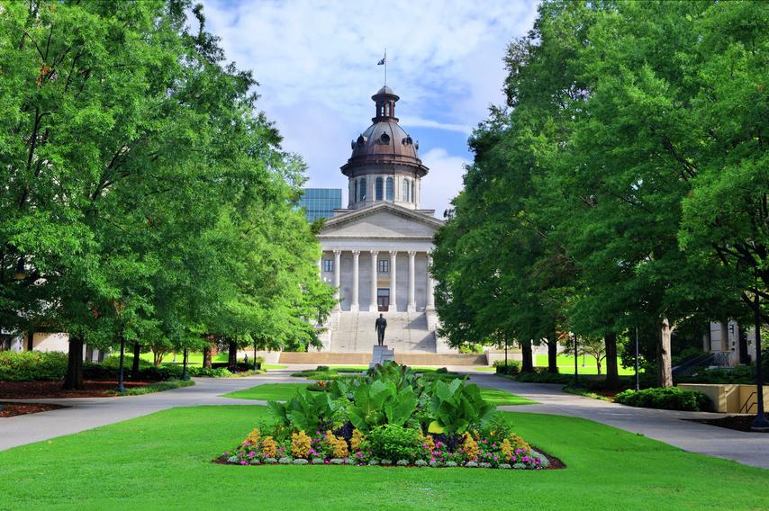 Columbia, South Carolina State House with landscaped grounds, green with flowers at the center, and bronze capped stone building