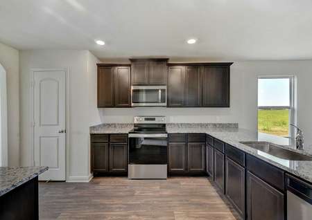 Frio kitchen with stainless steel stove and microwave, brown cabinets, and recessed light