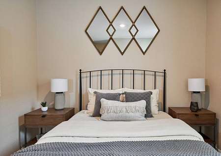 Staged bedroom with large bed, two nightstands, and wall decor.
