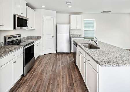 Kitchen with vinyl plank flooring, white cabinets and a large island.