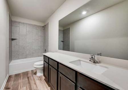 Jaguar bathroom with tile flooring, white countertop, and grey custom tile backsplash